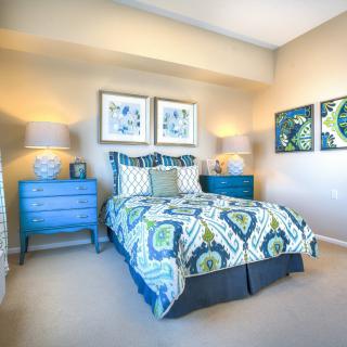 A modern bedroom with vibrant decor, featuring a colorful bedspread and matching art pieces on the walls.