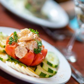 A gourmet salad featuring sliced tomatoes and cucumbers, garnished with fresh herbs.