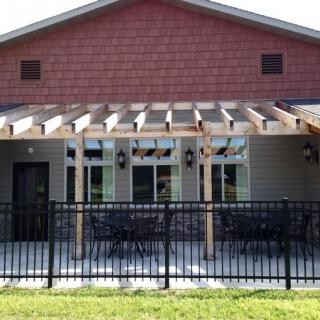 An outdoor seating area with a pergola and fenced patio attached to a building.