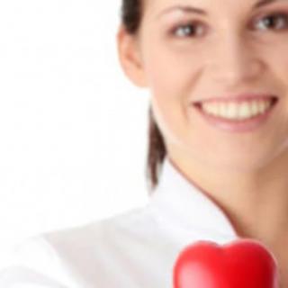 A smiling person holding a red heart, symbolizing healthcare.