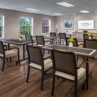 A well-organized classroom or conference room with tables and chairs arranged neatly, featuring a presentation screen and decorative flowers on the tables.