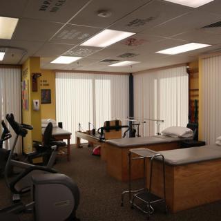 A rehabilitation room with exercise equipment and treatment tables for physical therapy.