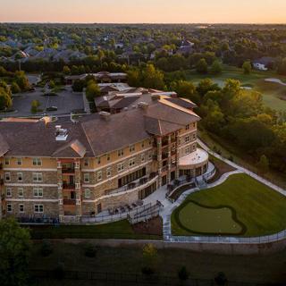 Aerial view of a large building surrounded by greenery at sunset.