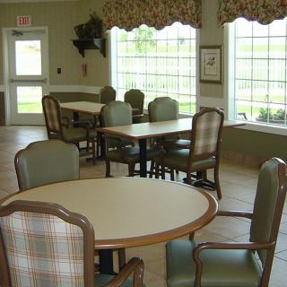 A cozy dining area with several tables and chairs near large windows.