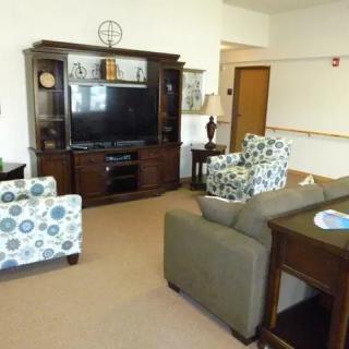 A cozy living room with a TV stand, sofa, and patterned armchairs.