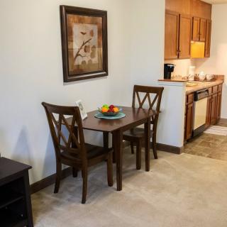 A cozy dining area with a wooden table and two chairs located next to a compact kitchen.
