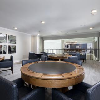 A modern game room featuring a round poker table surrounded by comfortable seating.