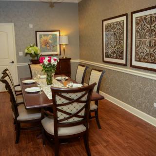 A beautifully decorated dining room featuring a wooden table, chairs, wall art, and fresh flowers.