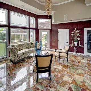 A luxurious living room with marble flooring, large windows, and elegant furnishings.