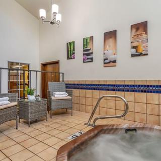 A tranquil indoor spa area featuring a jacuzzi, comfortable seating, and decorative wall art.