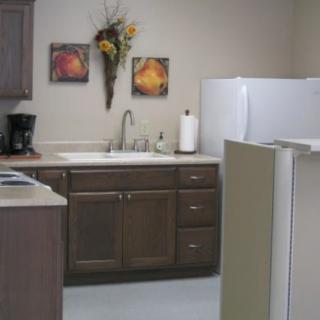 A kitchen with wooden cabinets, a sink, a coffee maker, and decorative wall art above the counter.