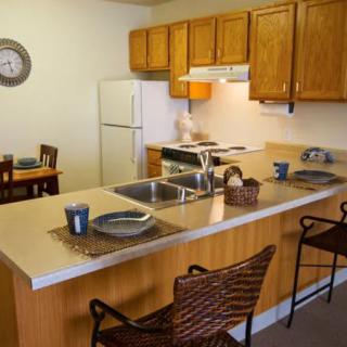 A cozy kitchen with wooden cabinets and a dining area featuring a countertop with bar stools.