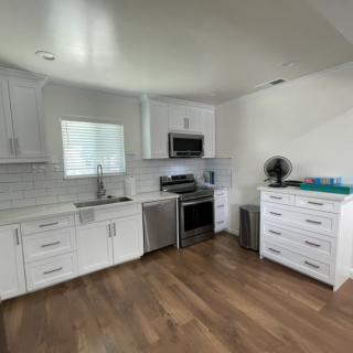 A modern kitchen with white cabinets and hardwood flooring.