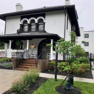 A charming two-story house with a porch and well-maintained landscaping.
