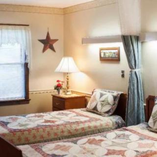 A cozy bedroom with twin beds featuring quilted bedspreads and a decorative star on the wall.
