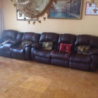 A spacious living room with a large leather sofa adorned with cushions, complemented by wall art and cozy decor.