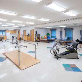 A spacious rehabilitation room equipped with various physical therapy and exercise equipment.