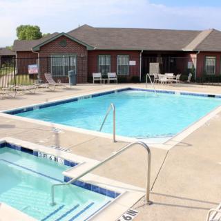 An outdoor pool area with a swimming pool, hot tub, and clubhouse seating.