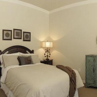 A cozy bedroom with a neatly made bed, decorative pillows, and a bedside lamp.