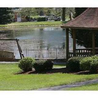 A serene garden scene featuring a gazebo, swing, and a lake in the background.