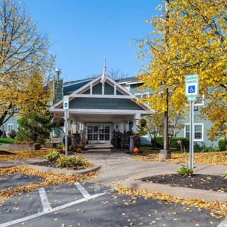 A building entrance surrounded by autumn foliage and a parking lot.
