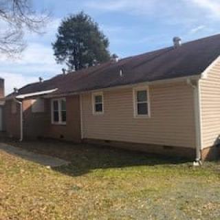 A single-story suburban house with a yard on a sunny day.