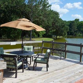 A scenic deck overlooking a lake, furnished with an umbrella and outdoor seating.