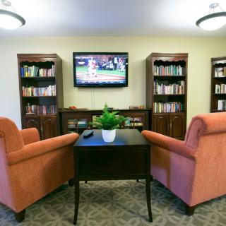 A cozy reading area with armchairs, bookshelves, and a television.