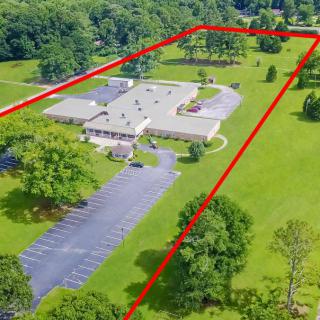 Aerial view of a property with outlined boundaries, featuring a building surrounded by greenery and a parking lot.