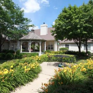 A beautiful garden with vibrant flowers and a gazebo on a sunny day.