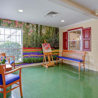 A cozy waiting area featuring a vibrant nature mural, comfortable benches, and a bright green floor.
