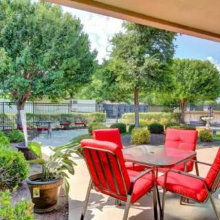 A cozy patio with red cushioned chairs overlooking a beautifully landscaped garden.