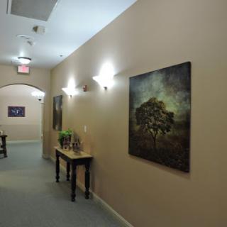 A serene hallway showcasing a piece of art on the wall, complemented by ambient lighting and a decorative table.