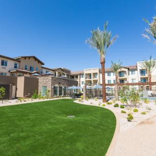 Modern apartment complex with well-maintained landscaping and palm trees.