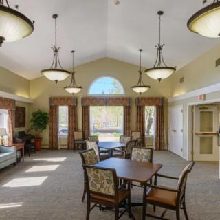 A spacious and well-lit lounge area with tables, chairs, and large windows.
