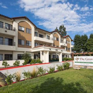 A modern residential building with well-maintained landscaping under a partly cloudy sky.