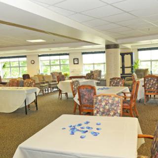 A bright and spacious community lounge area with tables and chairs set up for social activities.