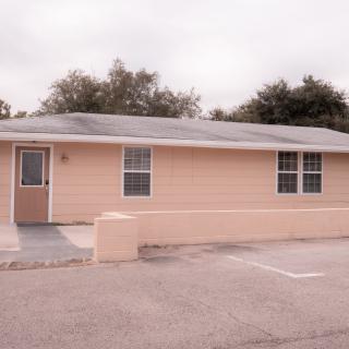 A small residential building with a simple facade, featuring two windows and a front door.