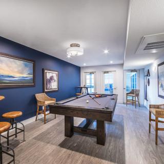 A stylish game room featuring a pool table, artwork on blue walls, and modern furnishings.