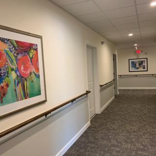 A hallway with colorful paintings and handrails, featuring an exit sign.