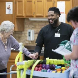 A healthcare worker interacts with elderly residents during an activity session.