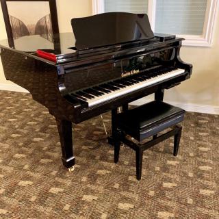 A black grand piano with a matching bench in a room.