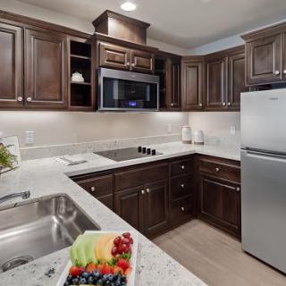 Modern kitchen with dark wood cabinetry and stainless steel appliances.