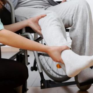 A caregiver assisting a person with a leg cast in a wheelchair.