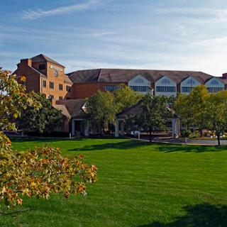 A picturesque view of a modern building surrounded by lush greenery and a clear blue sky.