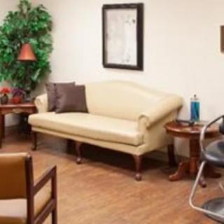 A cozy waiting room with a sofa, chairs, and decorative elements.