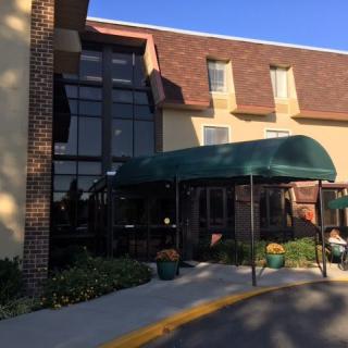 The entrance of a building with a green awning and large windows.