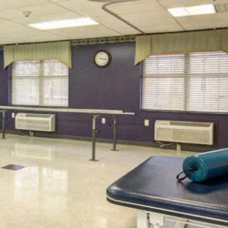A rehabilitation room with parallel bars and a fitness mat, designed for physical therapy exercises.