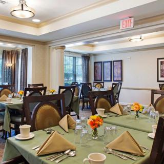 A well-set dining room with neatly arranged tables and chairs, featuring elegant decor and soft lighting.