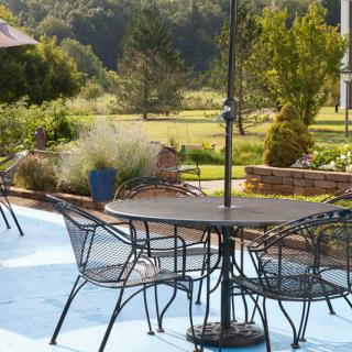 A serene outdoor patio with metal furniture overlooking a lush garden landscape.